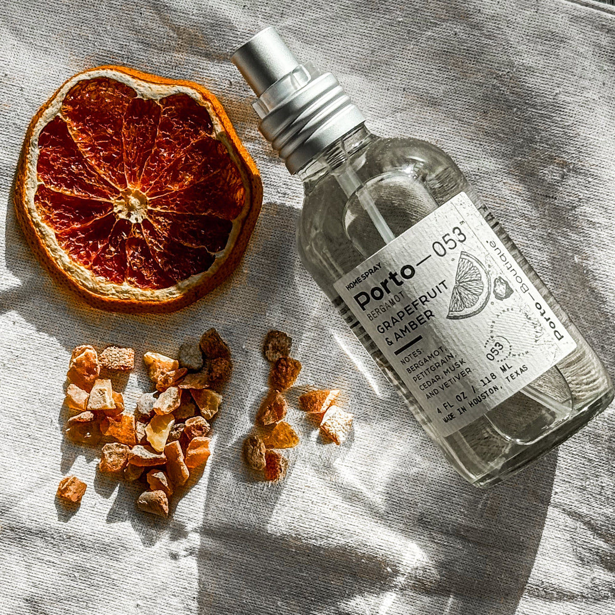 Porto-053 room spray on linen with a dried orange slice