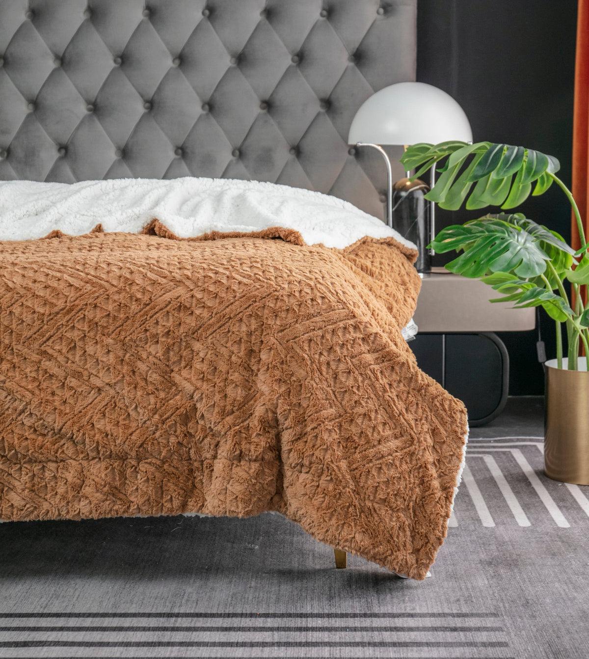 Caramel Chevron throw spread across a bed with a gray tufted headboard
