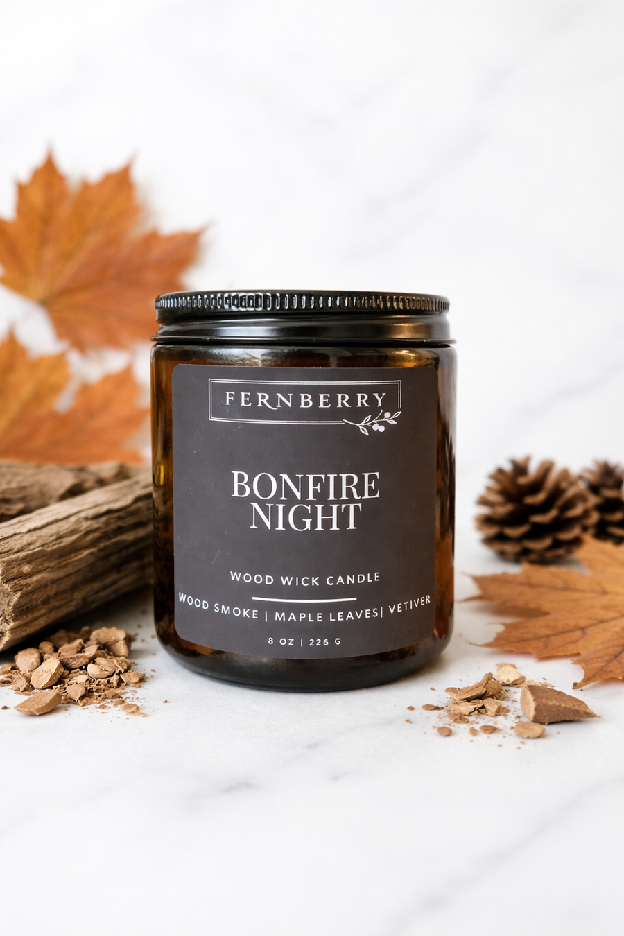 Bonfire Night candle in an amber jar with fall leaves, pinecones and wood