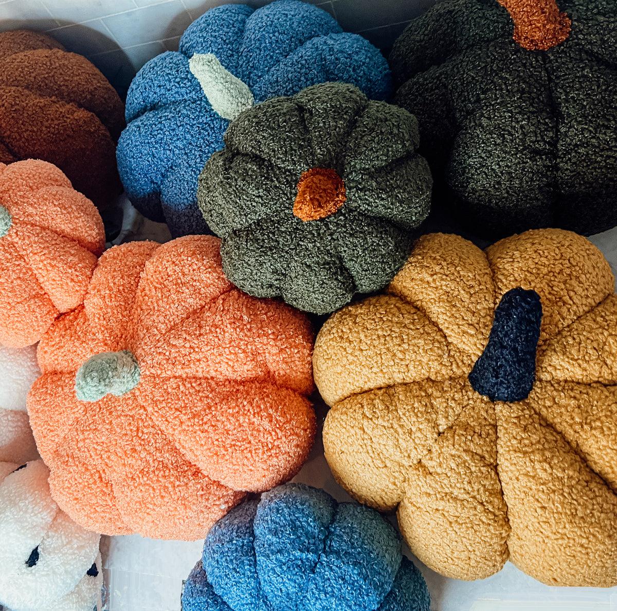 A pile of plush pumpkins in blue, green, orange and gold