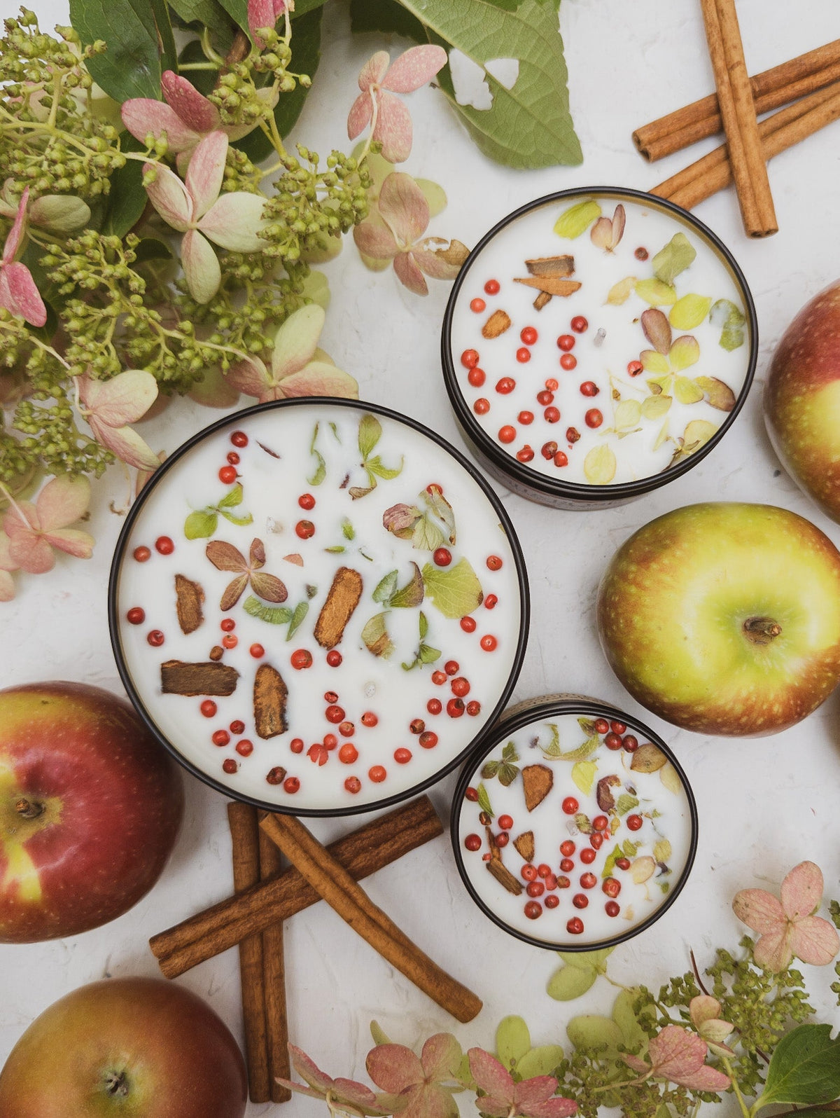 HARVEST candle tins in three sizes, seen from above, with apples and cinnamon sticks
