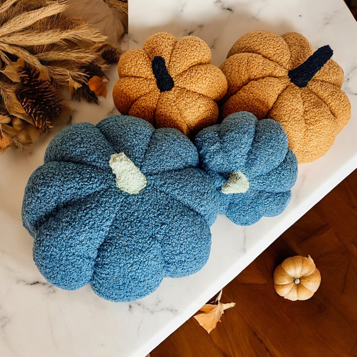 Blue and gold plush pumpkins on a table with dried leaves