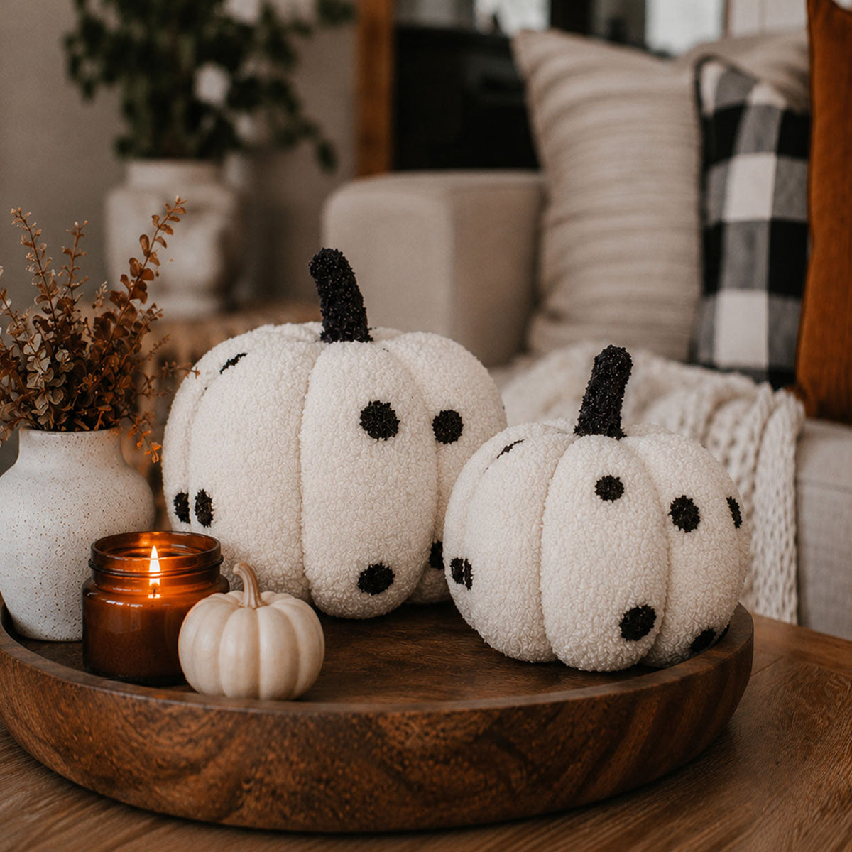 Two black-and-white polka dot plush pumpkins on a wooden tray