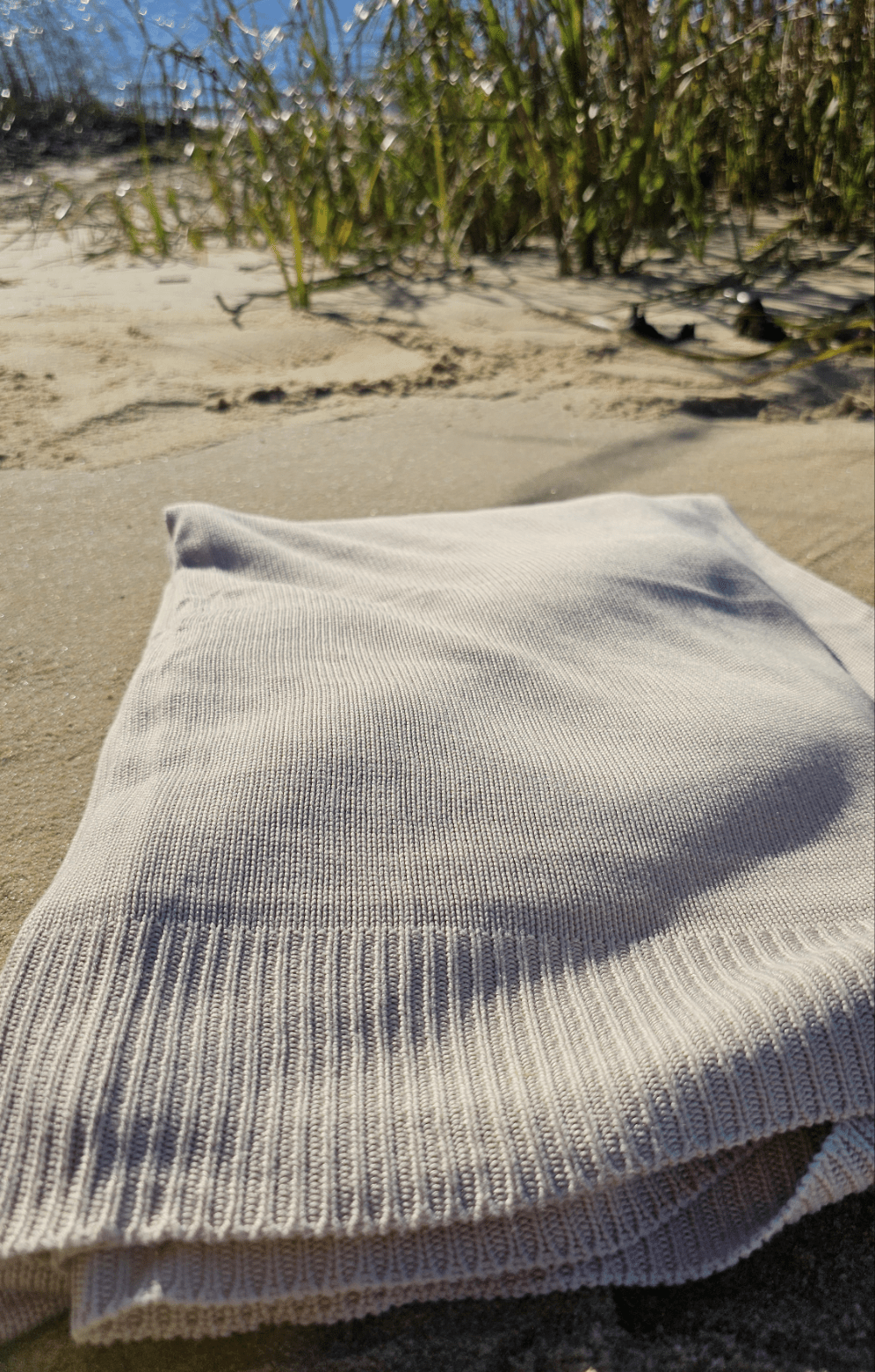Classic Drift throw folded on the sand beside dune grass