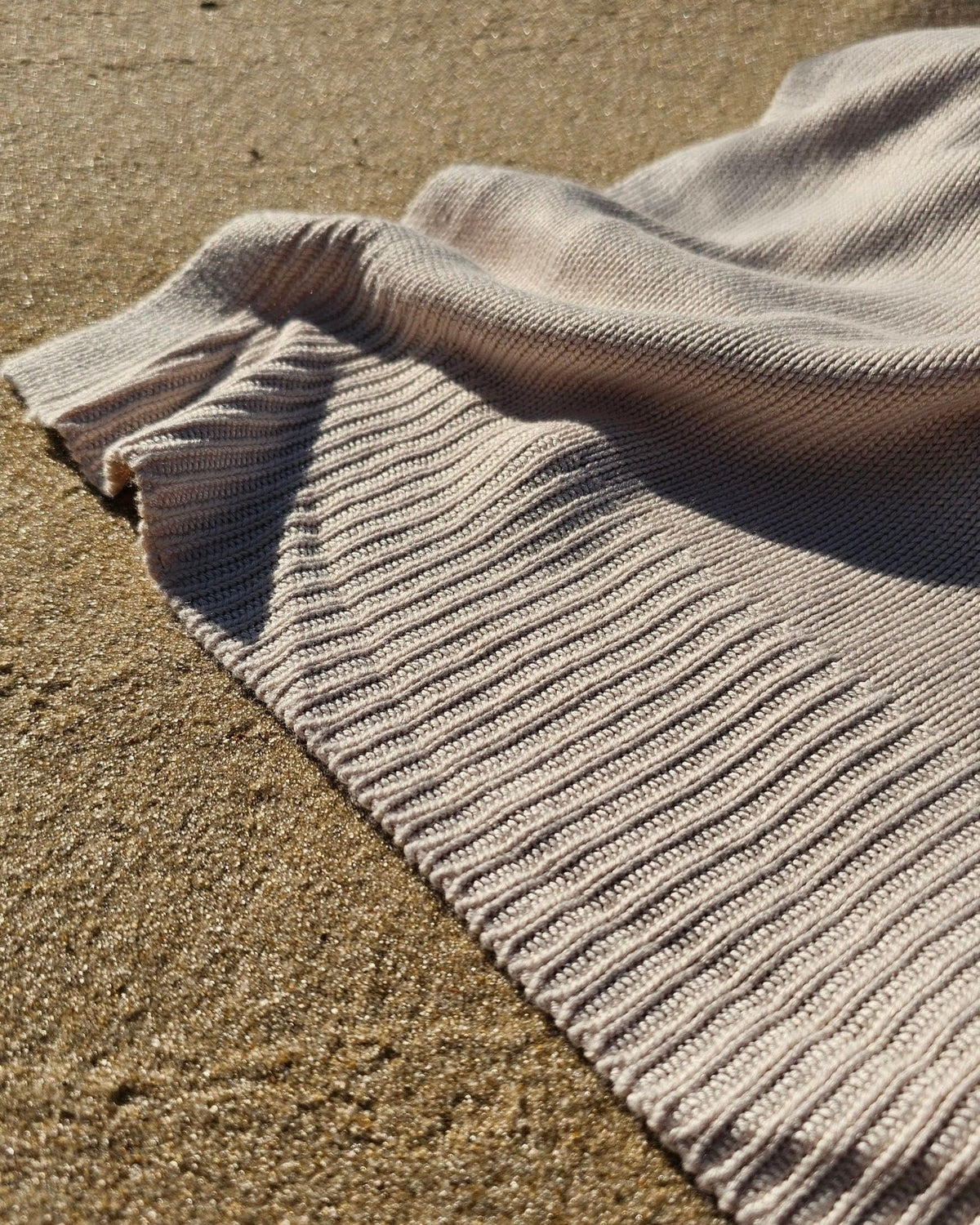 Classic Drift throw on the sand, showing its fine ribbed knit