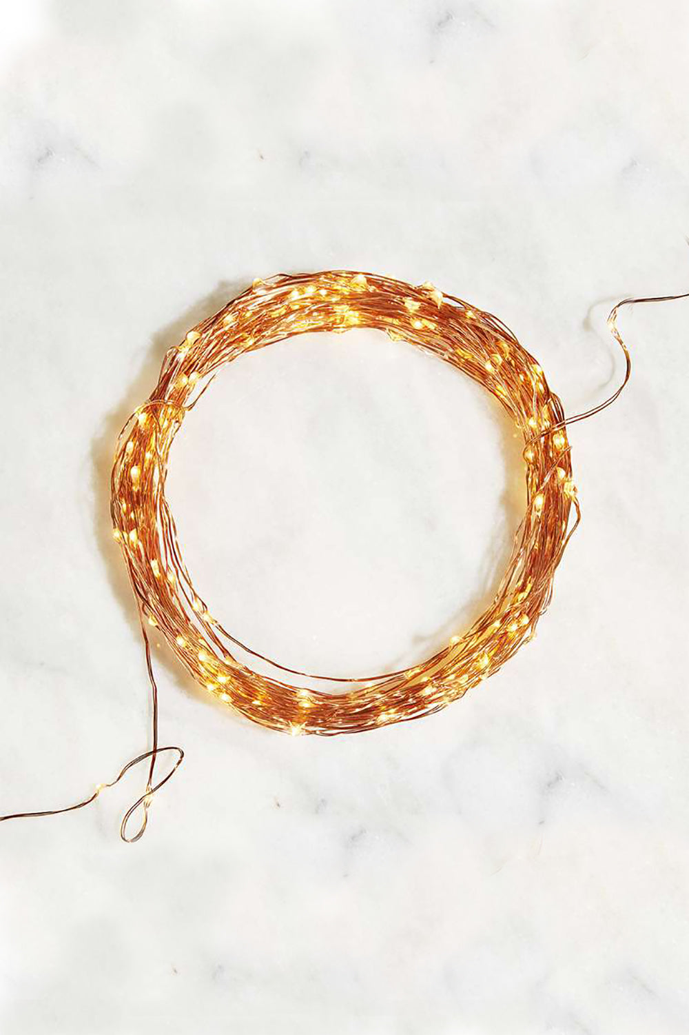 Coil of copper wire fairy lights on white marble