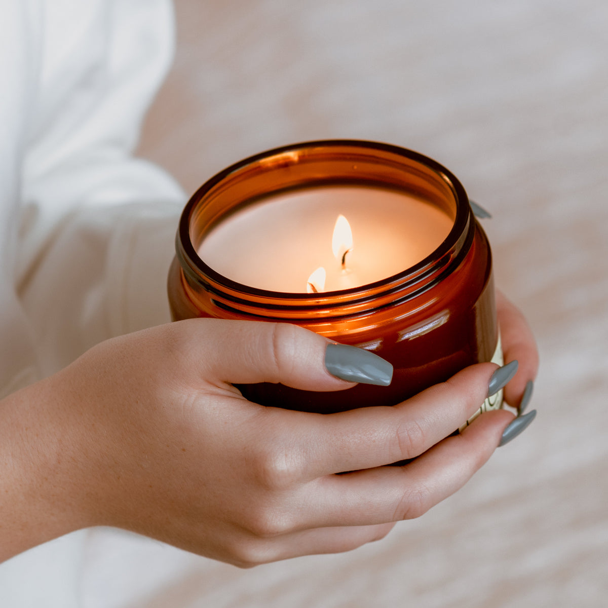 Hands holding a lit Fall Vibe Grande 2-wick candle