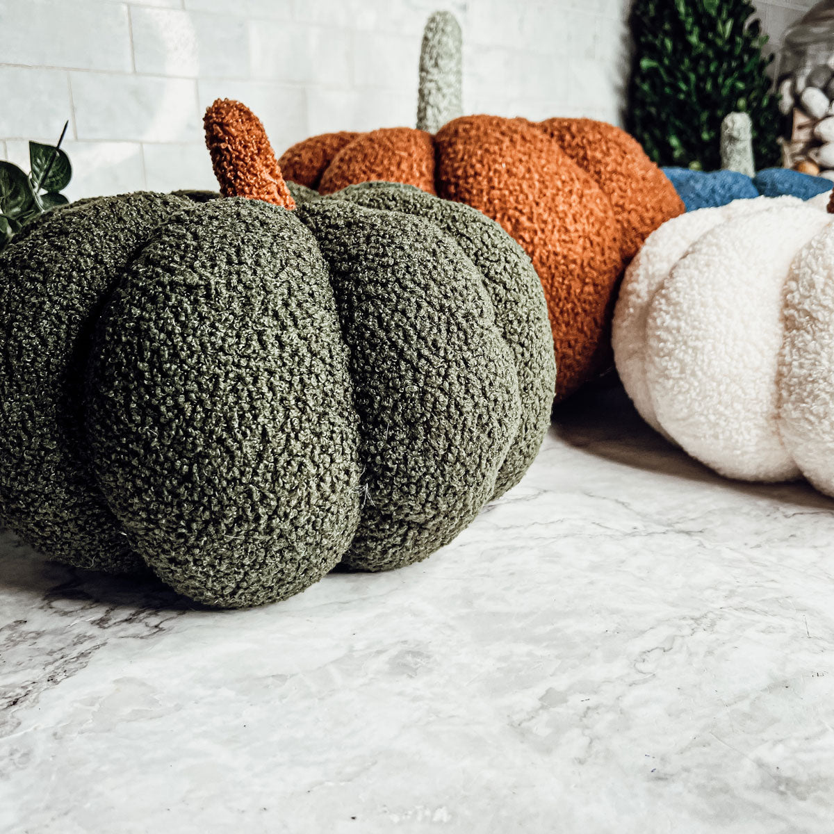 Green, orange and white plush pumpkins on a faux fur rug