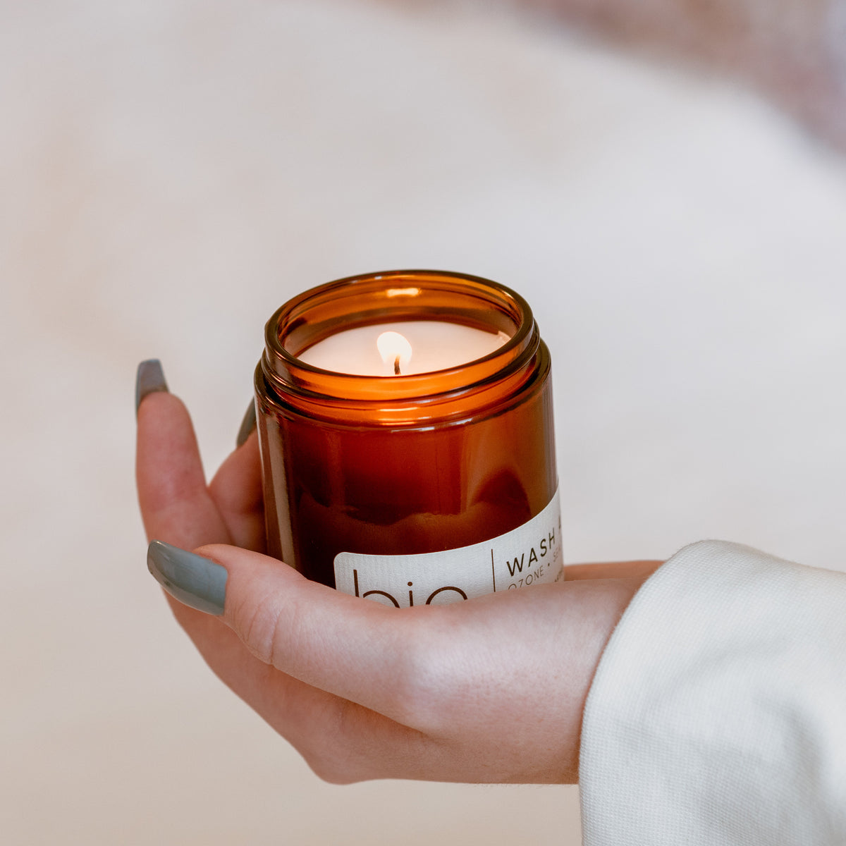 Hand holding a lit Fall Vibe Petite candle