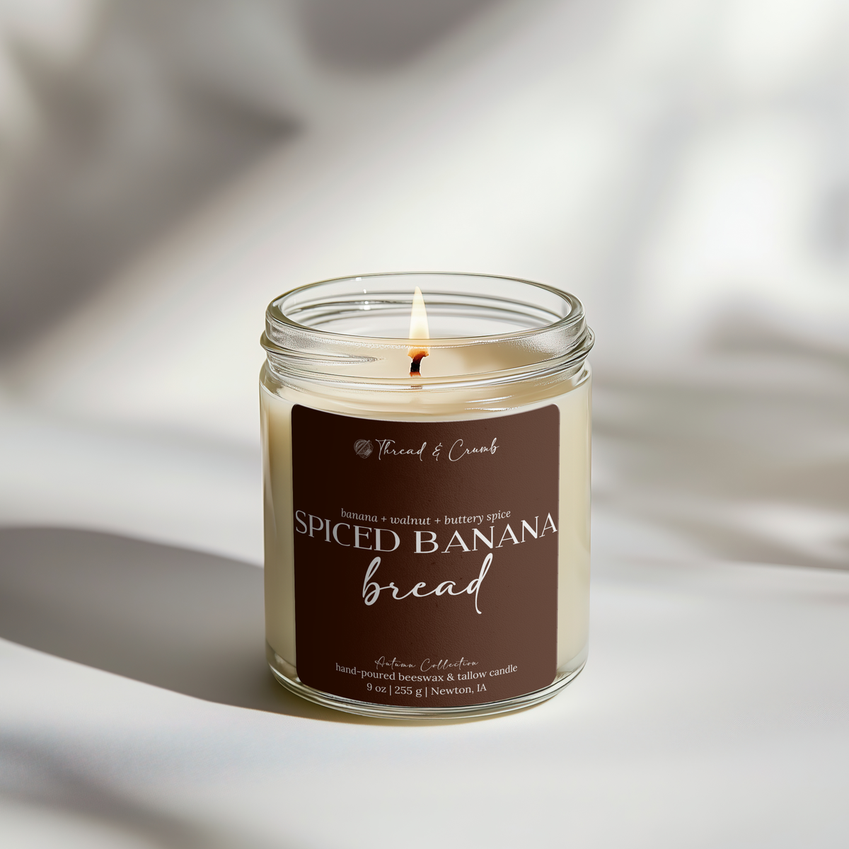Lit Spiced Banana Bread candle in a glass jar with a brown label