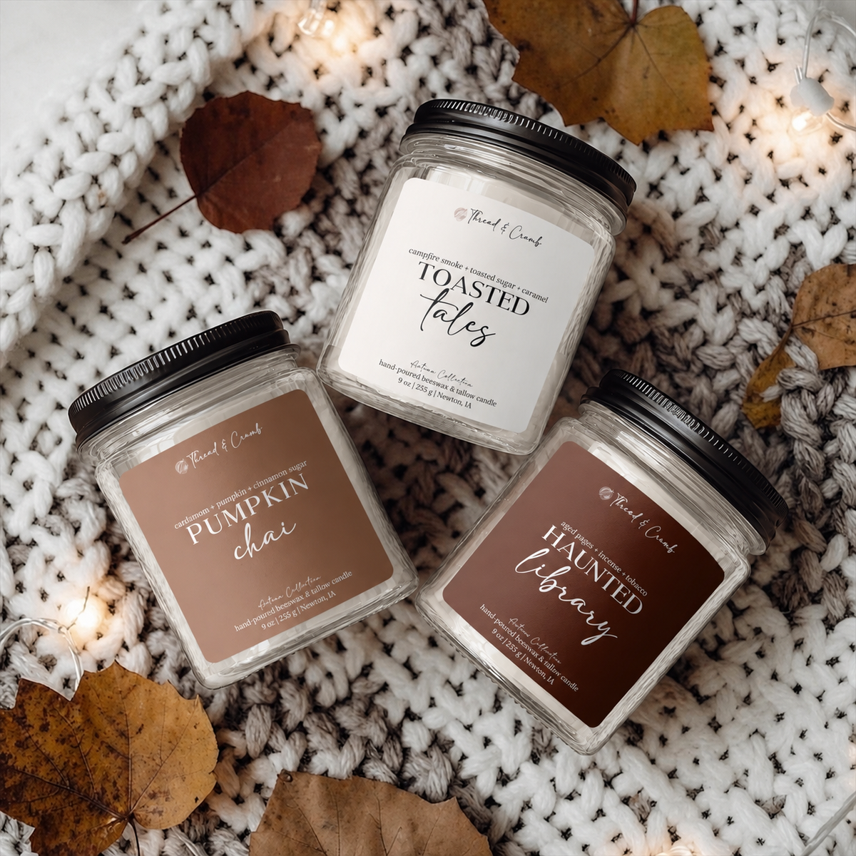 Three Thread & Crumb autumn candles on a chunky knit blanket with fallen leaves